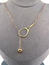 Load image into Gallery viewer, The newest design by Adeline - this unusual necklace is a tennis lovers delight. The solid gold ball threads through the racket and can be worn higher or lower on the neck. This piece was hand made in the jewelry district of Los Angeles by a fine jewel craft team. The racket is 1.5" long and the ball is 6mm around. Light yet strong enough to play (and win) in.