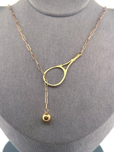 Load image into Gallery viewer, The newest design by Adeline - this unusual necklace is a tennis lovers delight.   The solid gold ball threads through the racket and can be worn higher or lower on the neck.  This piece was hand made in the jewelry district of Los Angeles by a fine jewel craft team.  The racket is 1.5&quot; long and the ball is 6mm around.  Light yet strong enough to play (and win) in.
