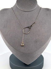 Load image into Gallery viewer, The newest design by Adeline - this unusual necklace is a tennis lovers delight.   The solid gold ball threads through the racket and can be worn higher or lower on the neck.  This piece was hand made in the jewelry district of Los Angeles by a fine jewel craft team.  The racket is 1.5&quot; long and the ball is 6mm around.  Light yet strong enough to play (and win) in.
