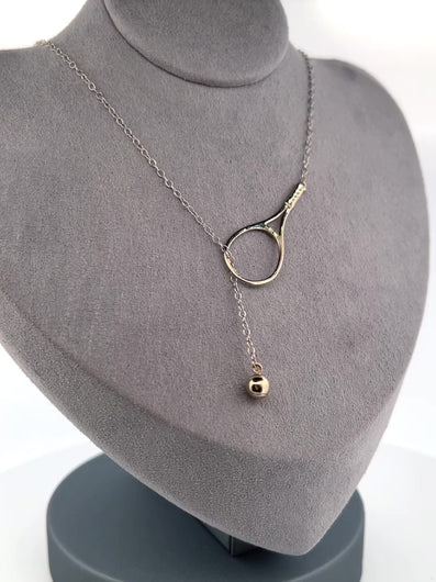 The newest design by Adeline - this unusual necklace is a tennis lovers delight.   The solid gold ball threads through the racket and can be worn higher or lower on the neck.  This piece was hand made in the jewelry district of Los Angeles by a fine jewel craft team.  The racket is 1.5" long and the ball is 6mm around.  Light yet strong enough to play (and win) in.